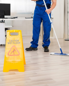 Low section of male janitor cleaning floor with mop in office