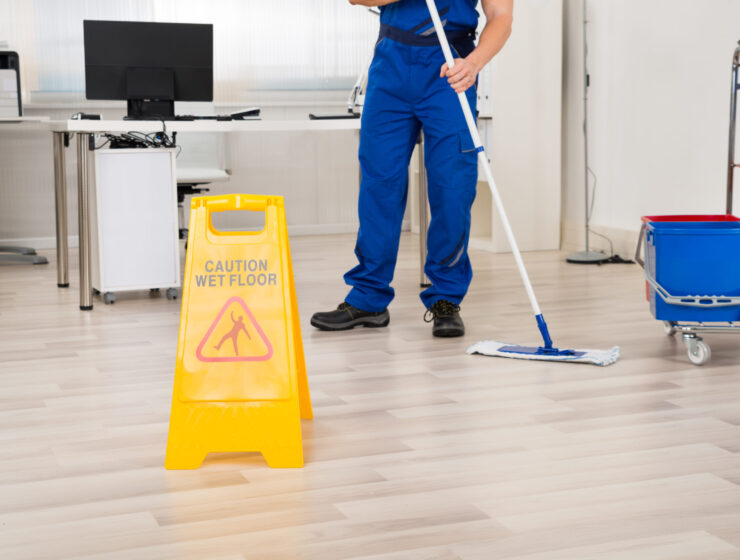 Low section of male janitor cleaning floor with mop in office