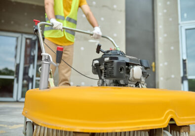 Cropped photo of a worker cleaning the outdoor floor tiles with a street sweeping machine